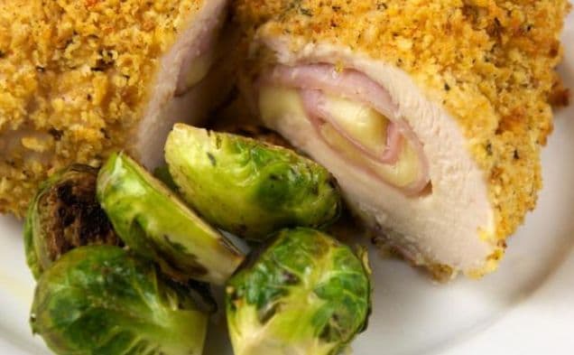 Crumbed chicken cordon bleu with ham and cheese beside roasted brussels sprouts